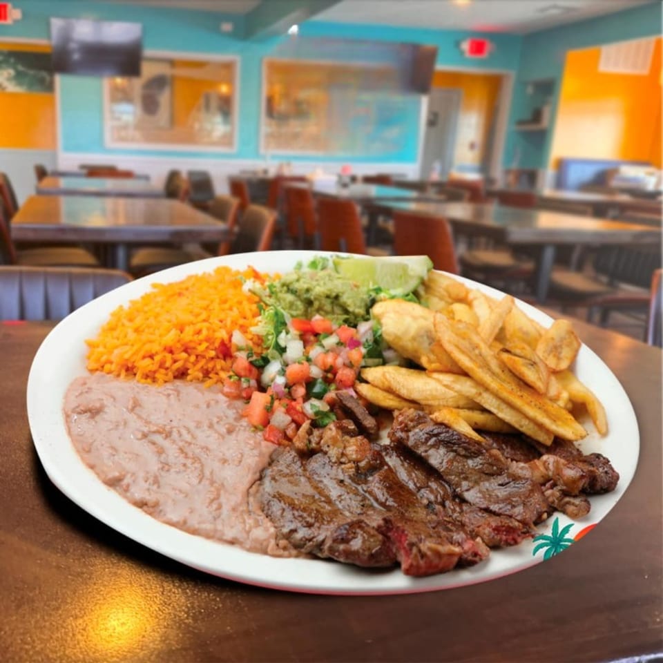 A Mexican steak platter with rice, beans, guacamole, pico de gallo, and fries in a restaurant.