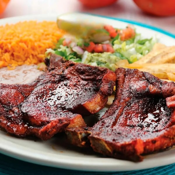 Mexican dish with three dark red ribs, orange rice, refried beans, and a side salad.